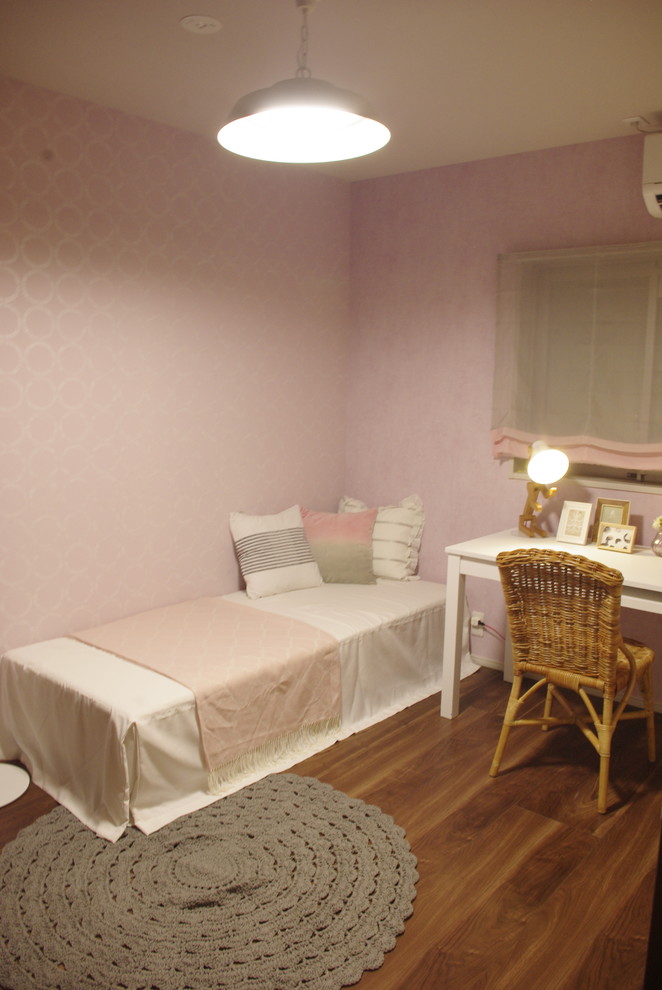 Cette photo montre une chambre de fille de 4 à 10 ans nature avec un bureau, un mur rose, un sol en contreplaqué et un sol marron.