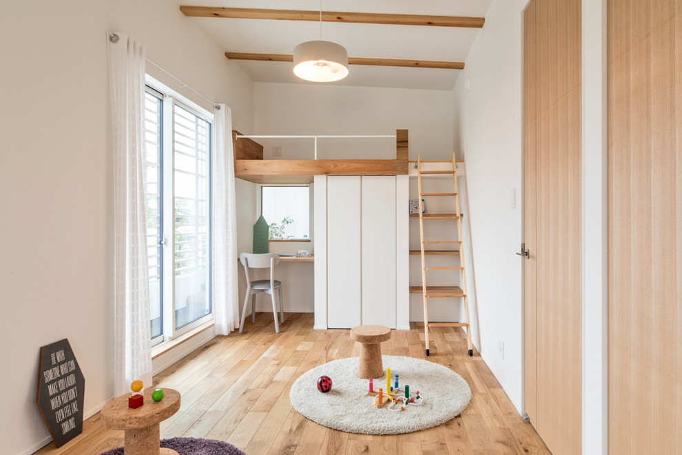 Scandi gender neutral children’s room in Nagoya with white walls, light hardwood flooring and beige floors.