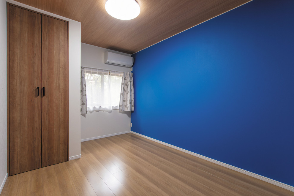 Bild på ett litet minimalistiskt barnrum, med blå väggar, mellanmörkt trägolv och brunt golv