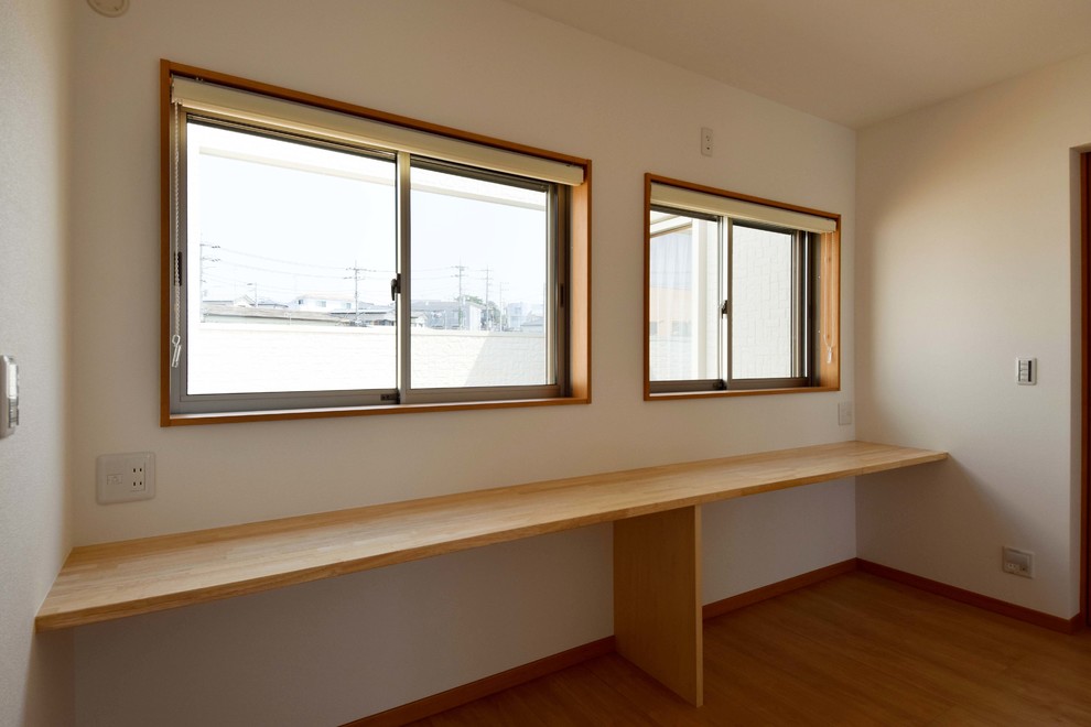 Diseño de habitación infantil unisex moderna de tamaño medio con escritorio, paredes blancas, suelo de madera oscura y suelo marrón