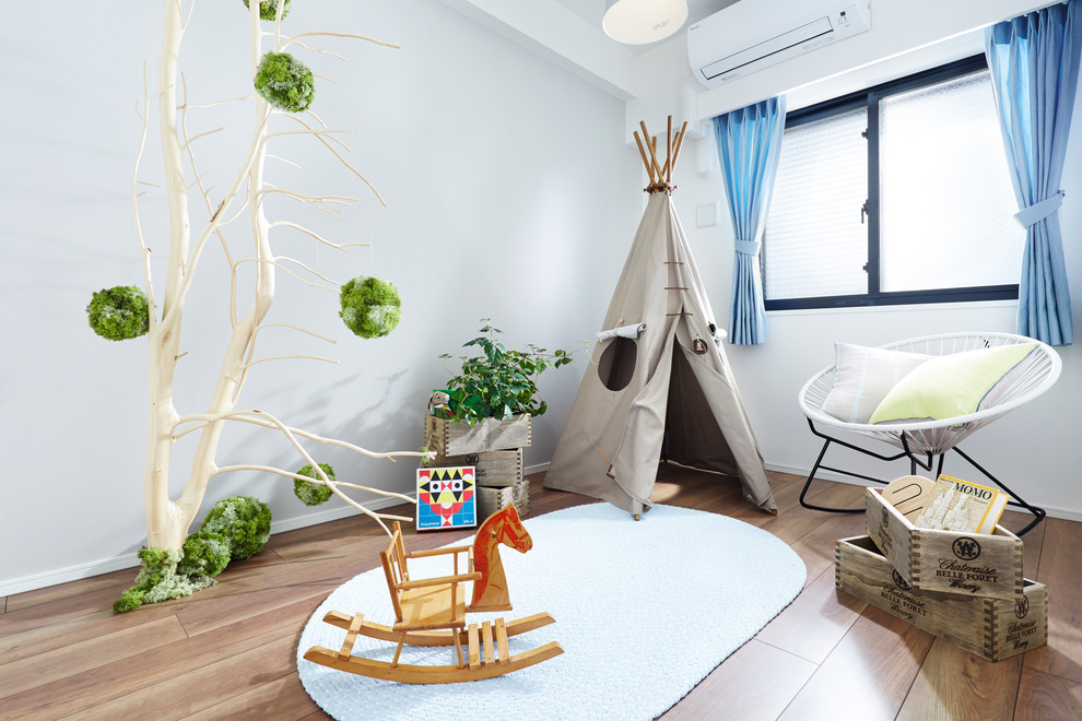 Bild på ett skandinaviskt könsneutralt småbarnsrum kombinerat med lekrum, med ljust trägolv och vita väggar