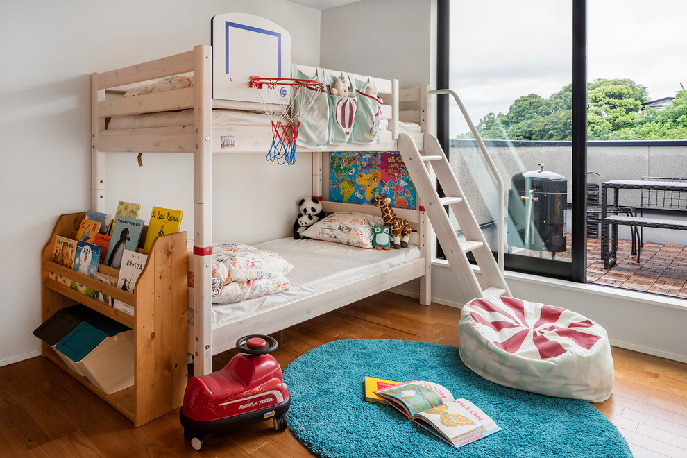 Example of a transitional gender-neutral medium tone wood floor kids' room design in Kobe with white walls
