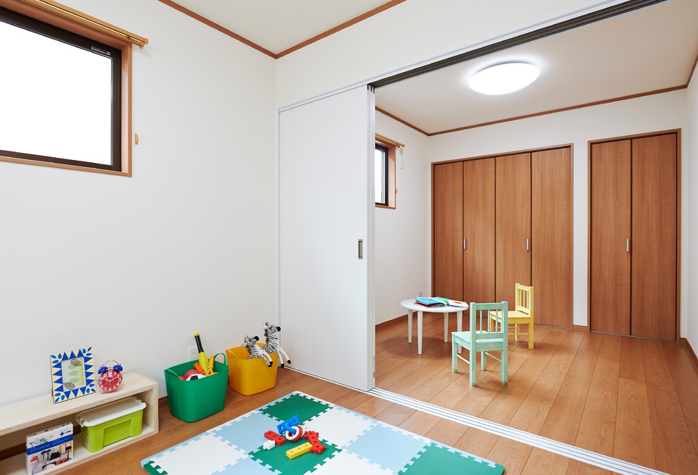 Пример оригинального дизайна: нейтральная детская с игровой в восточном стиле с белыми стенами и паркетным полом среднего тона для ребенка от 1 до 3 лет