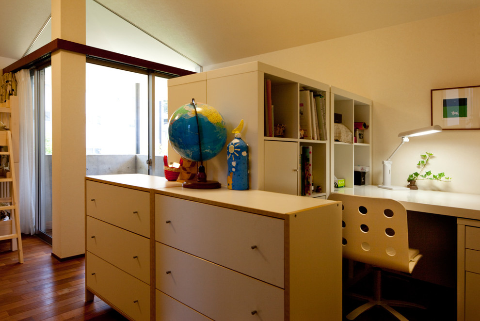 Imagen de habitación infantil unisex de 4 a 10 años minimalista de tamaño medio con escritorio, paredes blancas, suelo de madera clara y suelo marrón