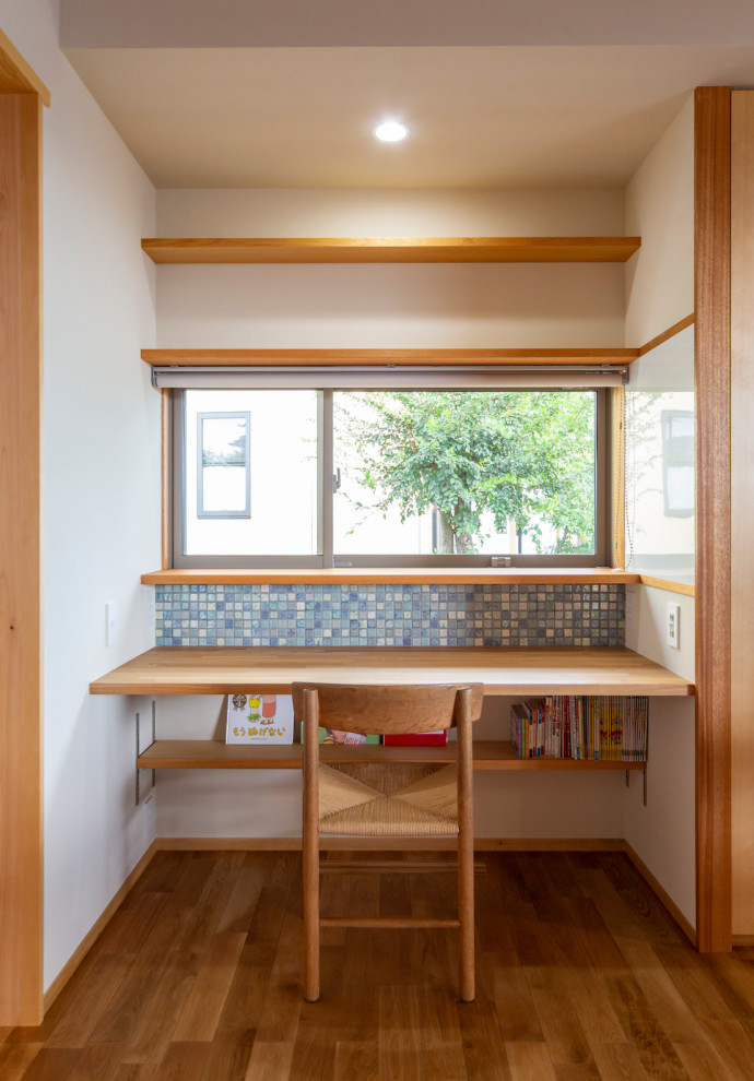 Bild på ett mellanstort orientaliskt könsneutralt barnrum kombinerat med skrivbord och för 4-10-åringar, med vita väggar, mellanmörkt trägolv och brunt golv