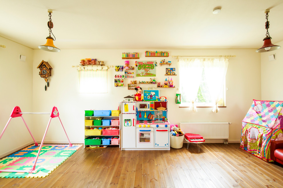 Immagine di una cameretta per bambini da 1 a 3 anni bohémian di medie dimensioni con pareti bianche e pavimento in legno massello medio