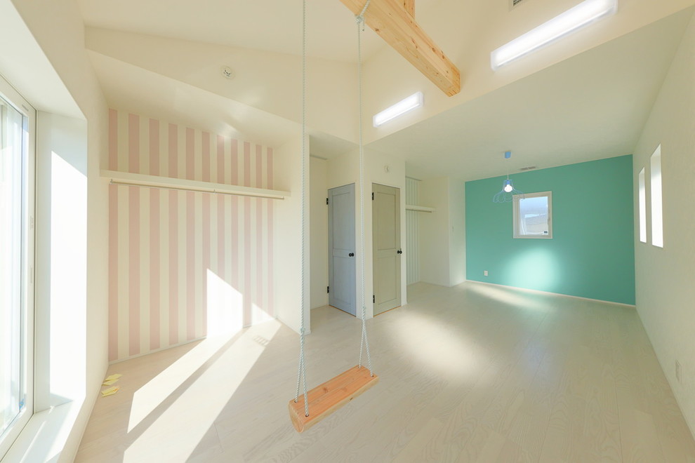 Scandinavian toddler’s room for girls in Other with plywood flooring.