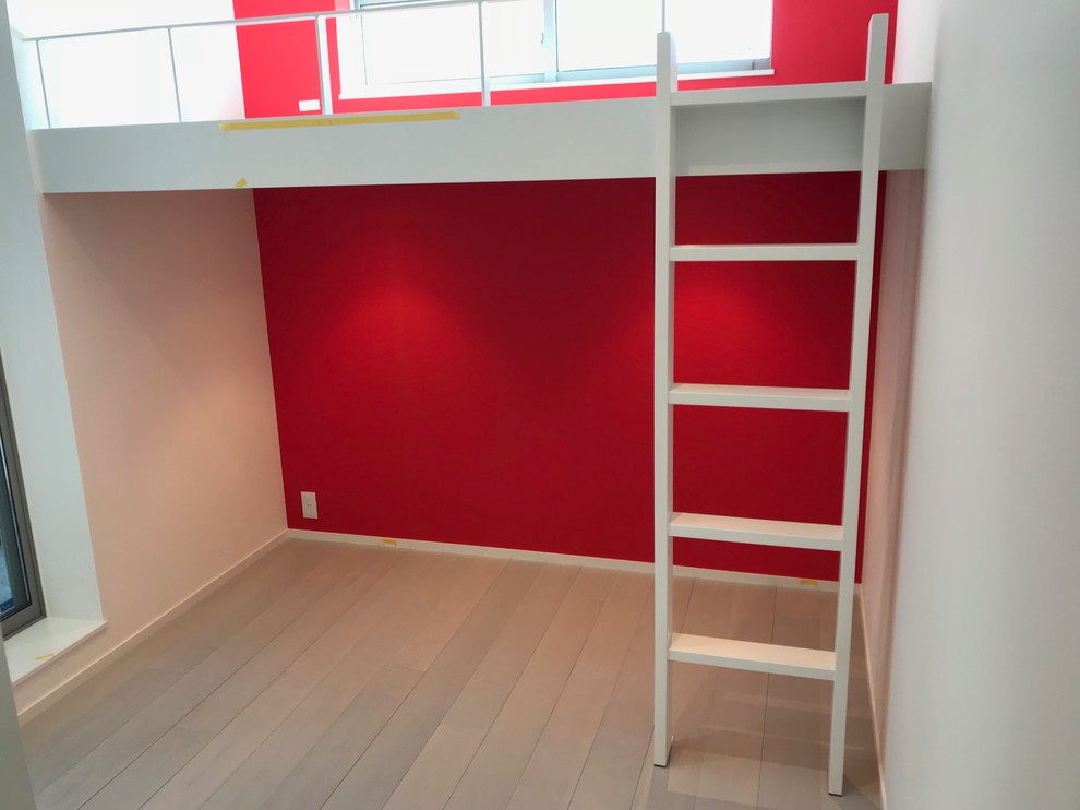 Cette image montre une chambre d'enfant minimaliste avec un mur rouge, un sol en contreplaqué et un sol gris.