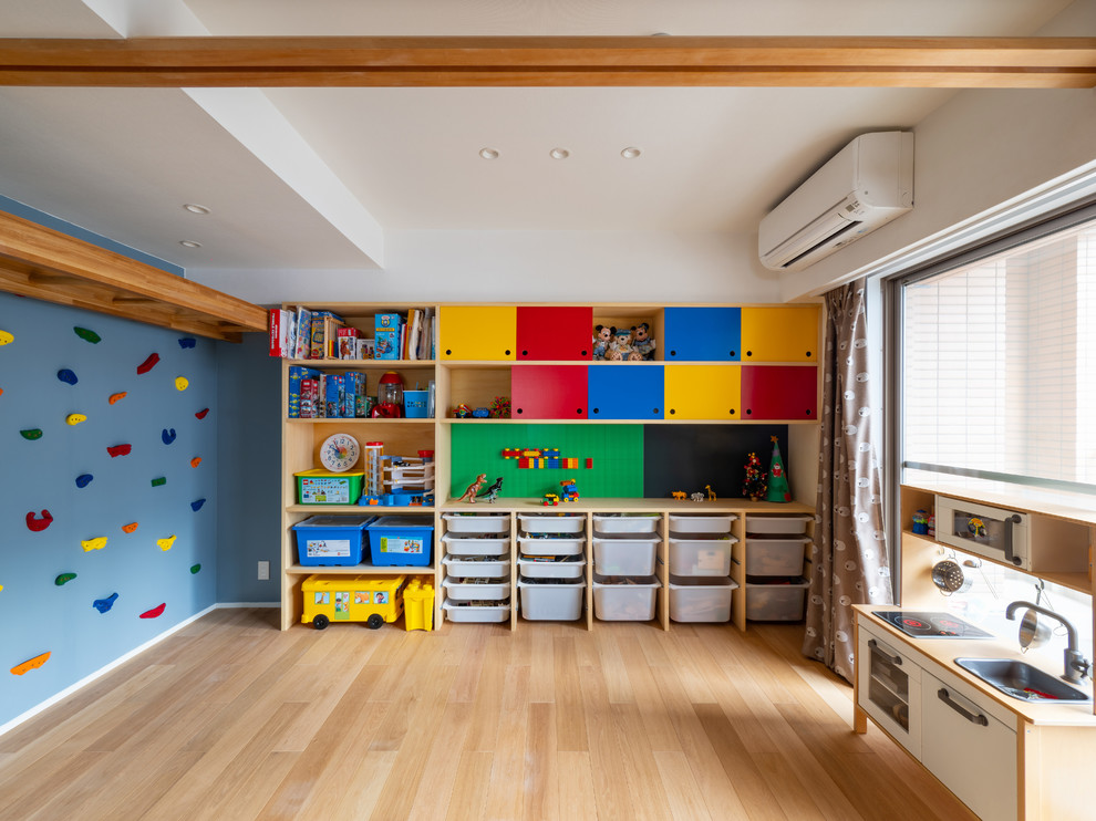 Inredning av ett minimalistiskt mellanstort könsneutralt barnrum kombinerat med lekrum och för 4-10-åringar, med blå väggar, plywoodgolv och brunt golv