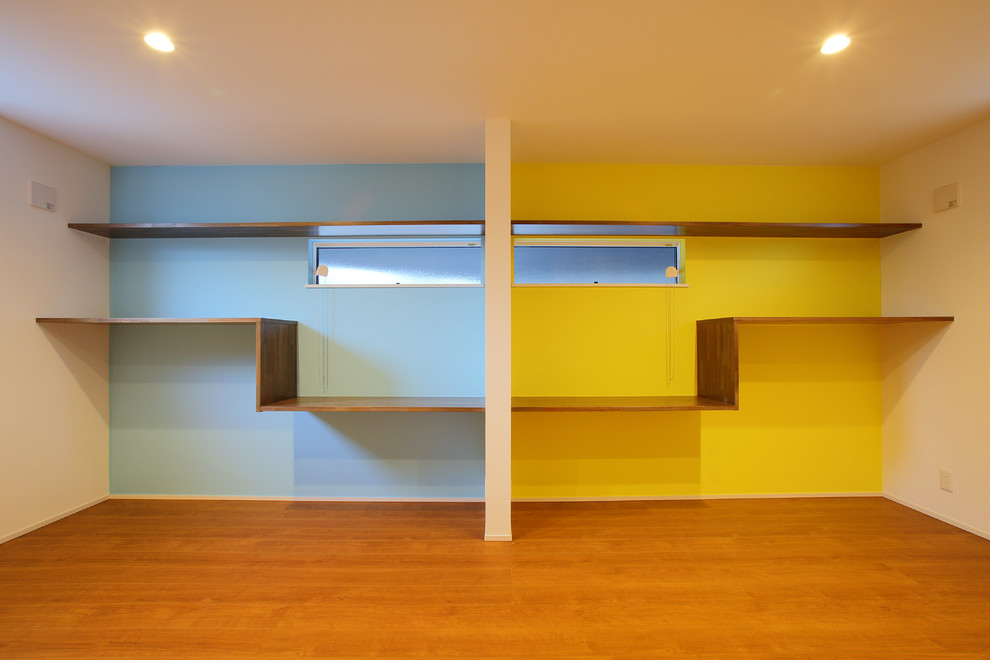 Inspiration för medelhavsstil könsneutrala barnrum kombinerat med skrivbord och för 4-10-åringar, med gula väggar, mellanmörkt trägolv och brunt golv