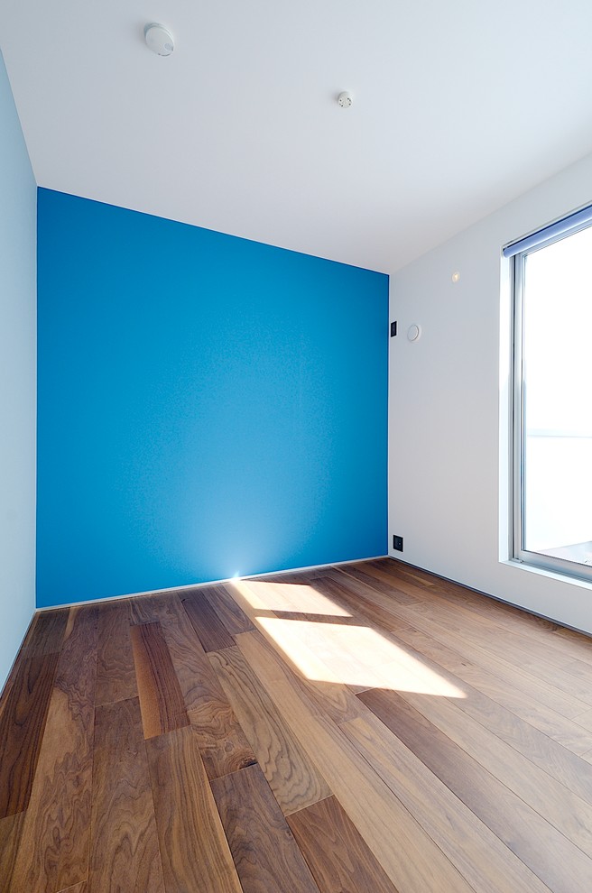 Ispirazione per una cameretta per bambini da 1 a 3 anni moderna con pareti blu, parquet scuro e pavimento beige