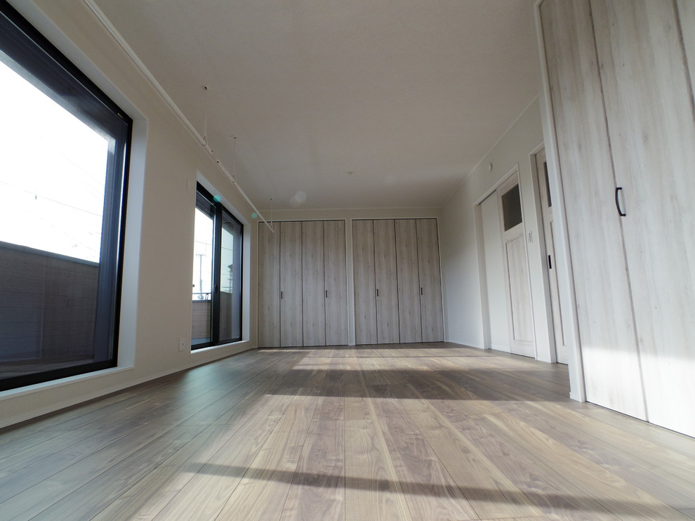 Exempel på ett minimalistiskt barnrum kombinerat med lekrum, med beige väggar, plywoodgolv och brunt golv