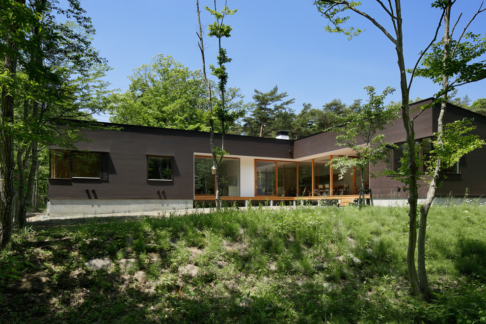 Пример оригинального дизайна: одноэтажный, деревянный, коричневый частный загородный дом в стиле модернизм с односкатной крышей и металлической крышей