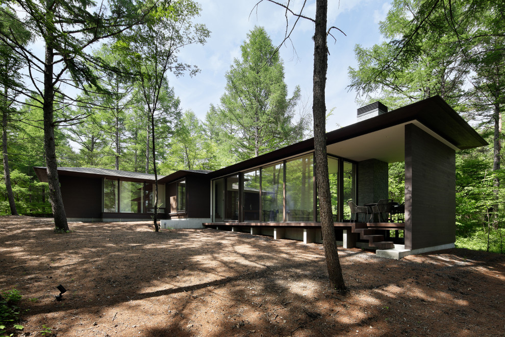 Réalisation d'une façade de maison marron minimaliste en bois à niveaux décalés avec un toit à quatre pans et un toit en métal.
