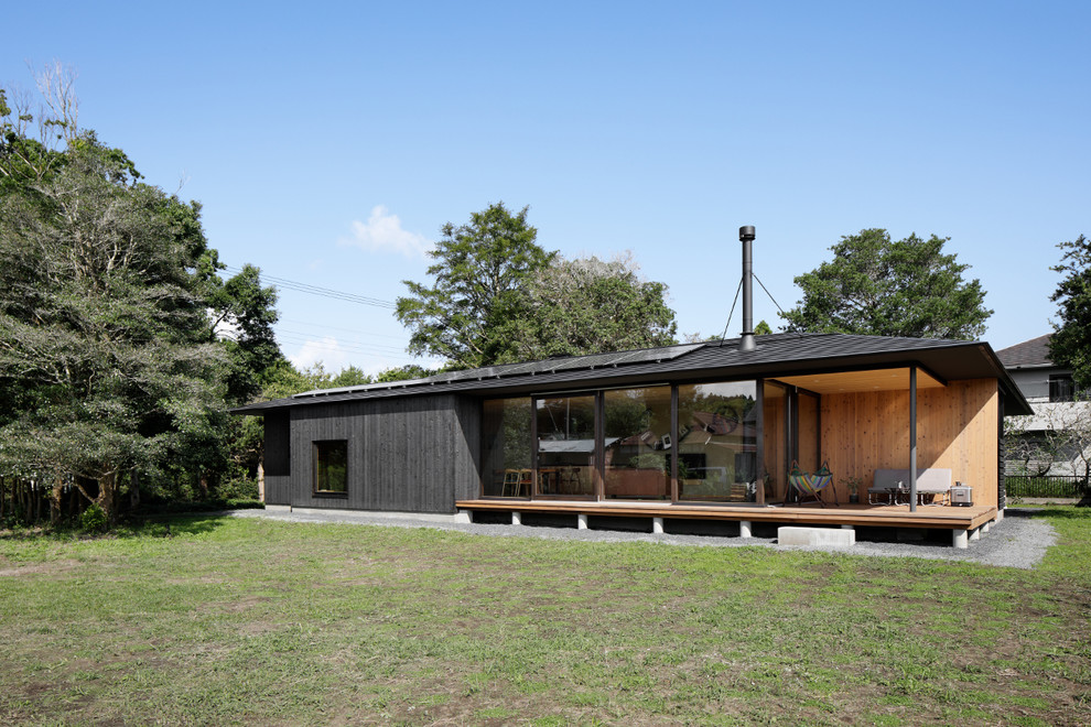 На фото: деревянный, черный, одноэтажный частный загородный дом в восточном стиле с двускатной крышей и металлической крышей