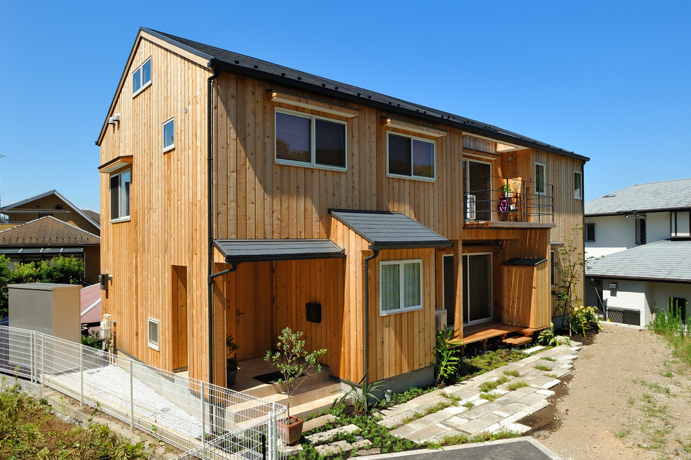 Foto de fachada de casa contemporánea de dos plantas con revestimiento de madera y tejado a dos aguas