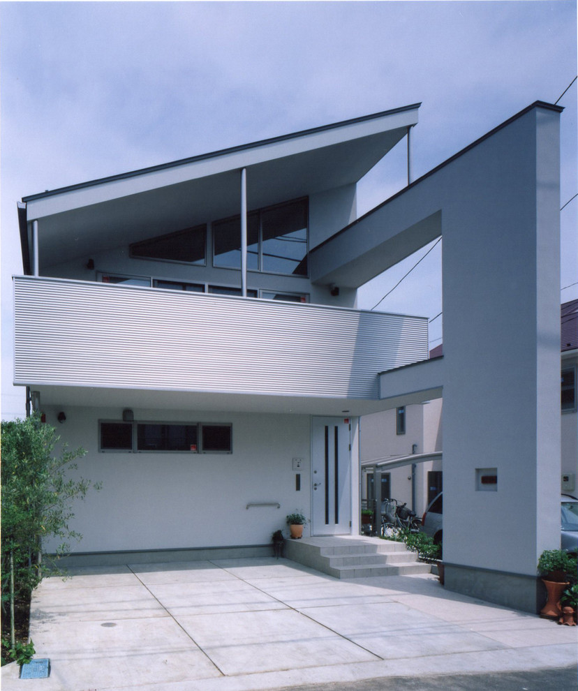 Cette image montre une grande façade de maison métallique et blanche minimaliste à un étage avec un toit en appentis.