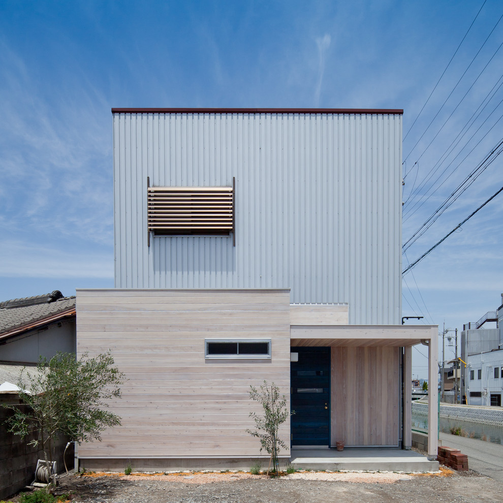 Idées déco pour une façade de maison bleue contemporaine en bois avec un toit plat.