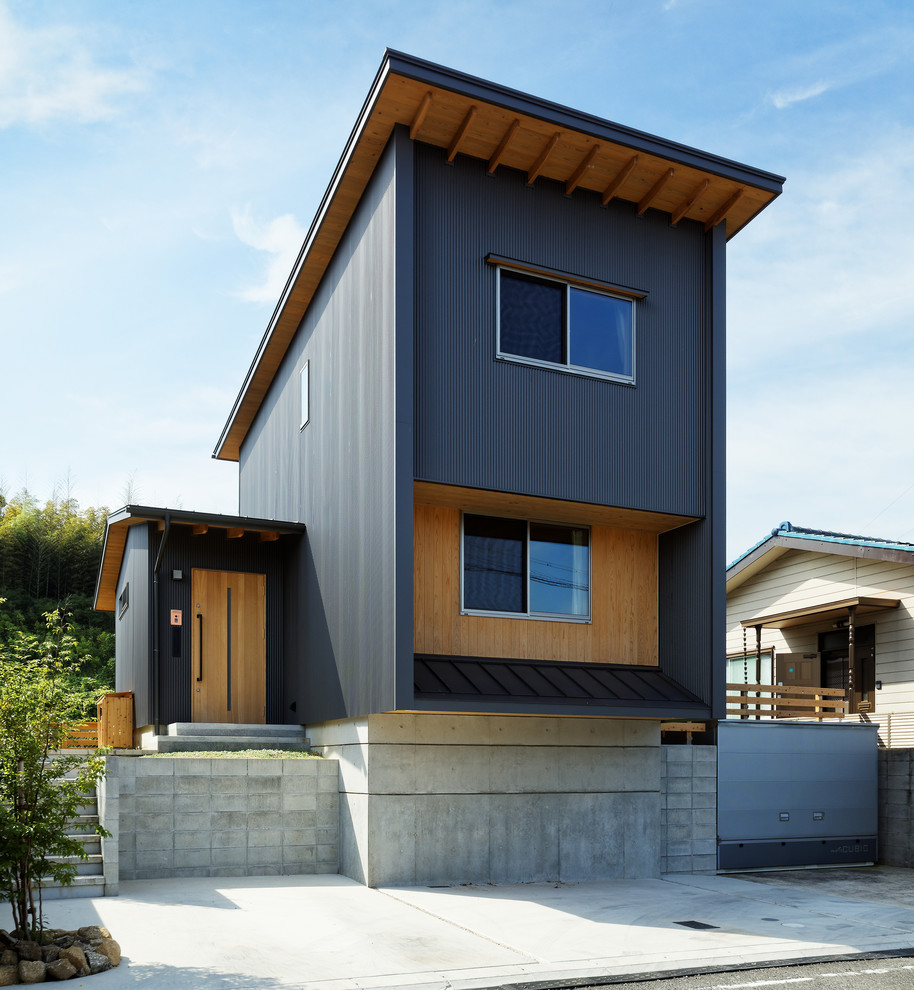 На фото: двухэтажный, черный дом в стиле модернизм с облицовкой из металла и односкатной крышей с