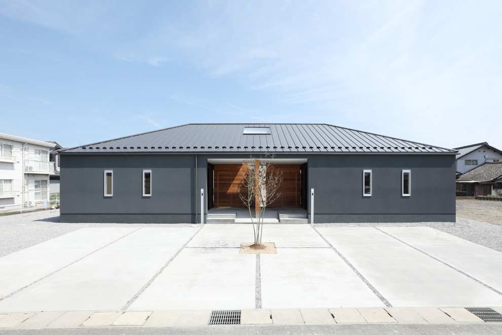 Réalisation d'une grande façade de maison grise nordique en béton de plain-pied avec un toit à quatre pans, un toit en métal et boîte aux lettres.