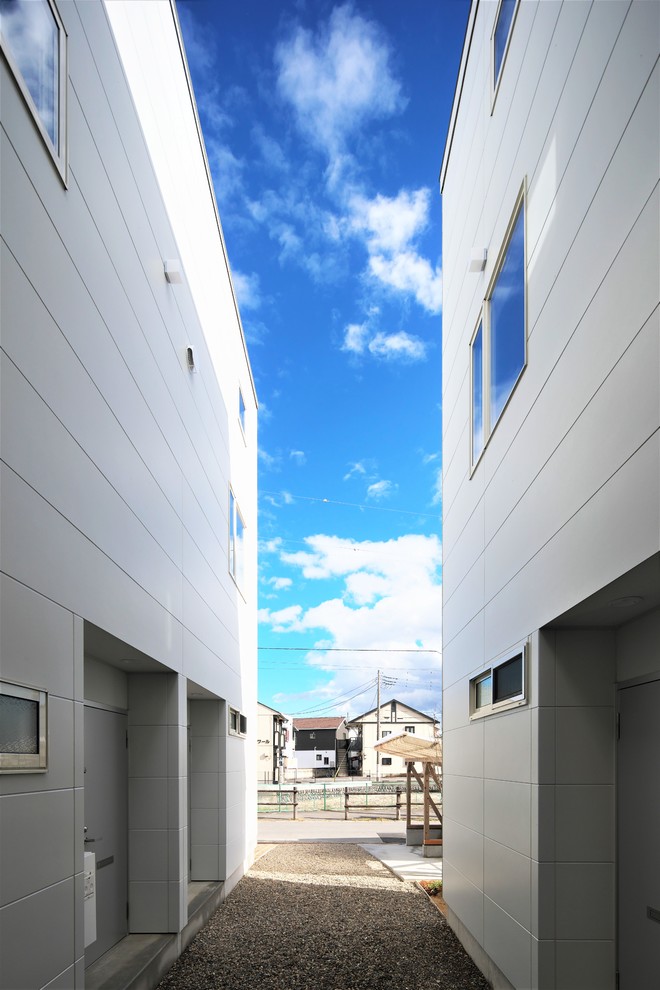 Modelo de fachada de piso blanca de estilo zen pequeña de dos plantas con revestimiento de metal, tejado de un solo tendido y tejado de metal