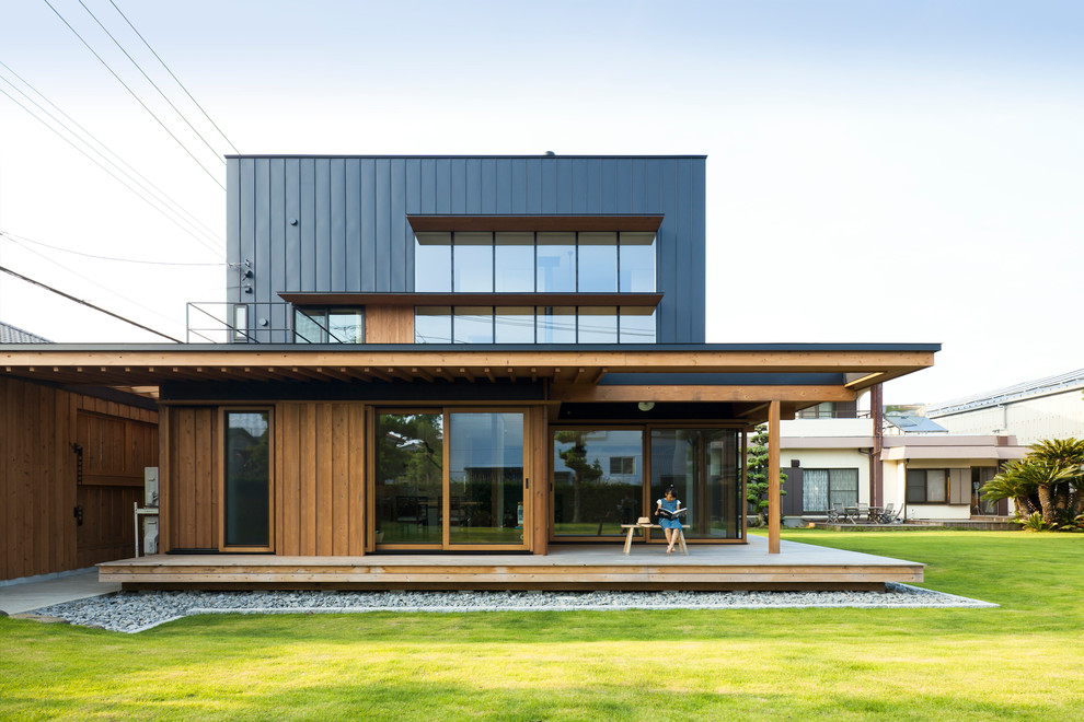 Foto della facciata di una casa marrone contemporanea a due piani con rivestimento in legno e tetto piano