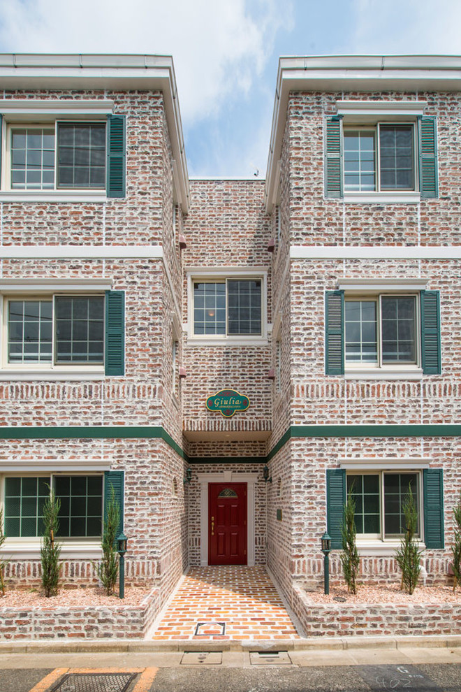 Esempio della facciata di un appartamento grande rosa classico a tre piani con rivestimento in mattoni