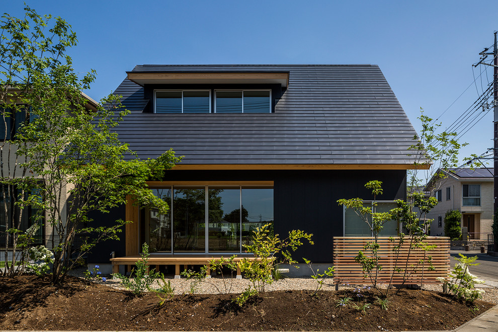 Idée de décoration pour une façade de maison noire asiatique à un étage avec un toit à deux pans et un toit en métal.