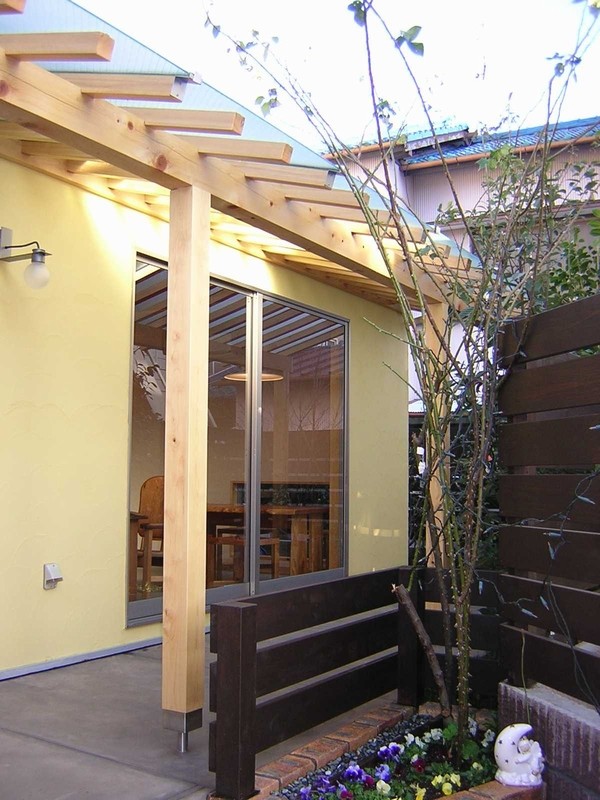 На фото: маленький, двухэтажный, желтый частный загородный дом в скандинавском стиле с односкатной крышей и металлической крышей для на участке и в саду
