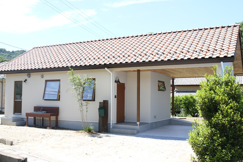 Exemple d'une façade de maison beige romantique de plain-pied avec un toit à deux pans et un toit en tuile.