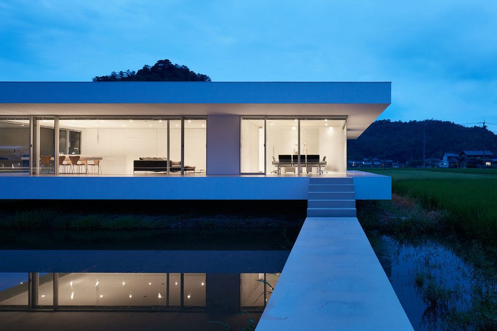 Стильный дизайн: одноэтажный, белый частный загородный дом в стиле модернизм с плоской крышей - последний тренд