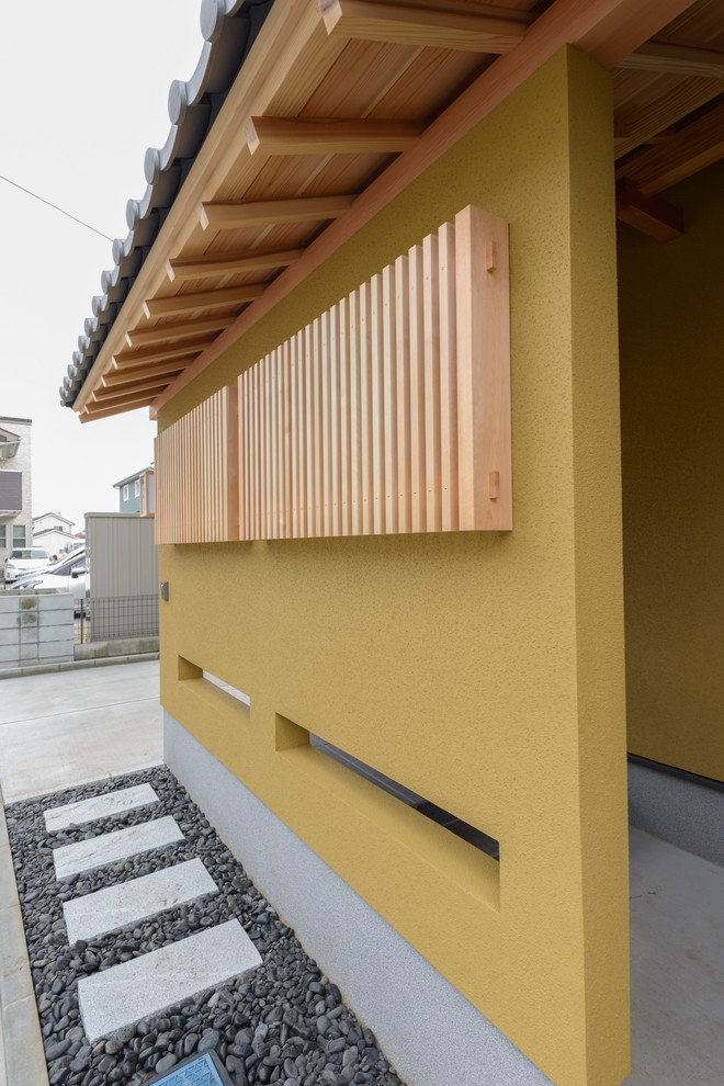 Ejemplo de fachada de casa beige asiática pequeña de dos plantas con tejado a dos aguas y tejado de teja de barro