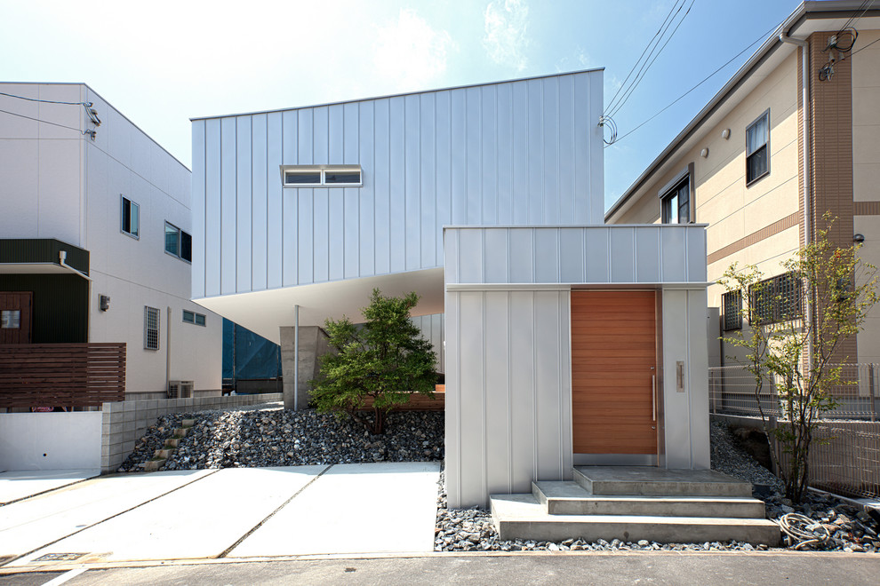 Cette image montre une façade de maison métallique et blanche urbaine de taille moyenne et à un étage avec un toit plat.