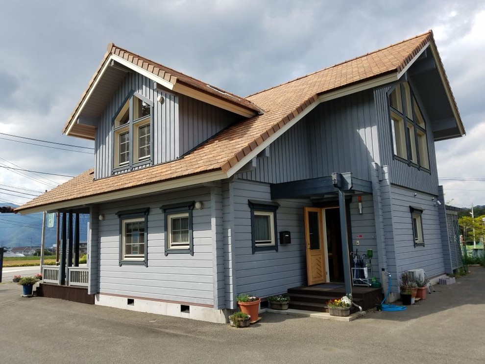 Стильный дизайн: синий дом из бревен в классическом стиле с двускатной крышей и коричневой крышей - последний тренд