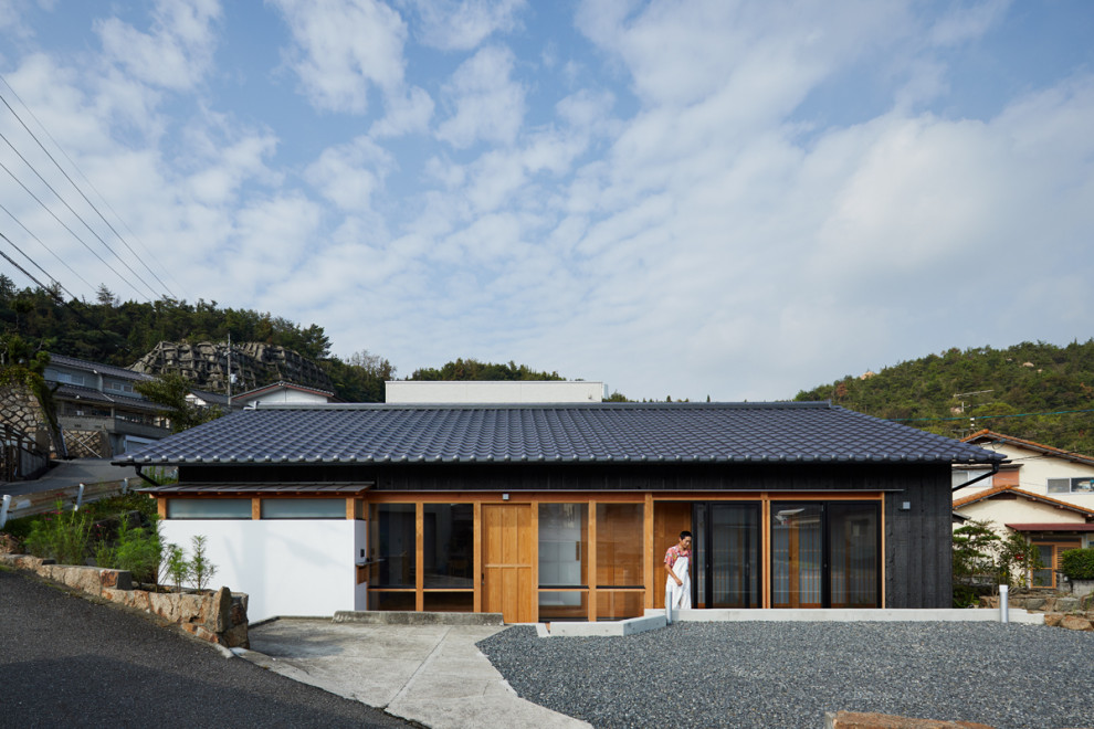 Cette photo montre une petite façade de maison noire craftsman en bois de plain-pied avec un toit à deux pans et un toit en tuile.