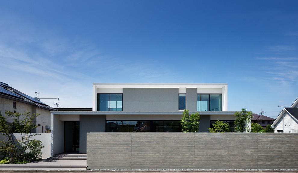 Cette image montre une grande façade de maison blanche minimaliste en béton à un étage avec un toit en appentis et un toit en métal.