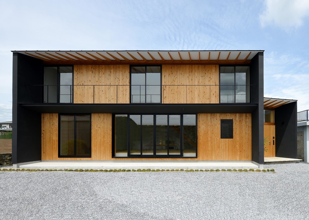 Exemple d'une façade de maison noire tendance en bois à un étage avec un toit à deux pans et un toit en métal.