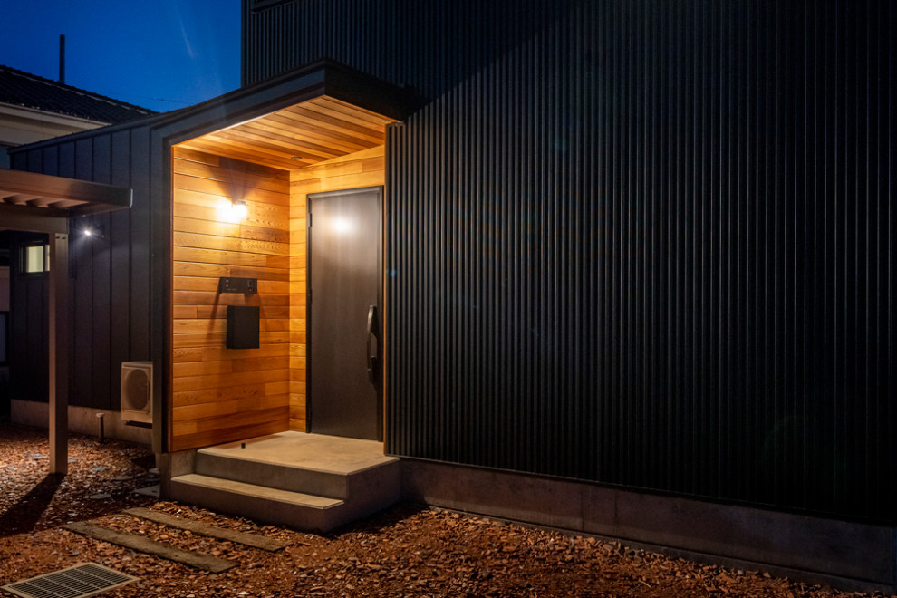 Ejemplo de fachada de casa negra minimalista de tamaño medio de dos plantas con revestimiento de metal, tejado de un solo tendido y tejado de metal
