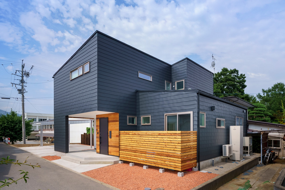 Aménagement d'une façade de maison métallique et noire contemporaine de taille moyenne et à un étage avec un toit en appentis et un toit en métal.