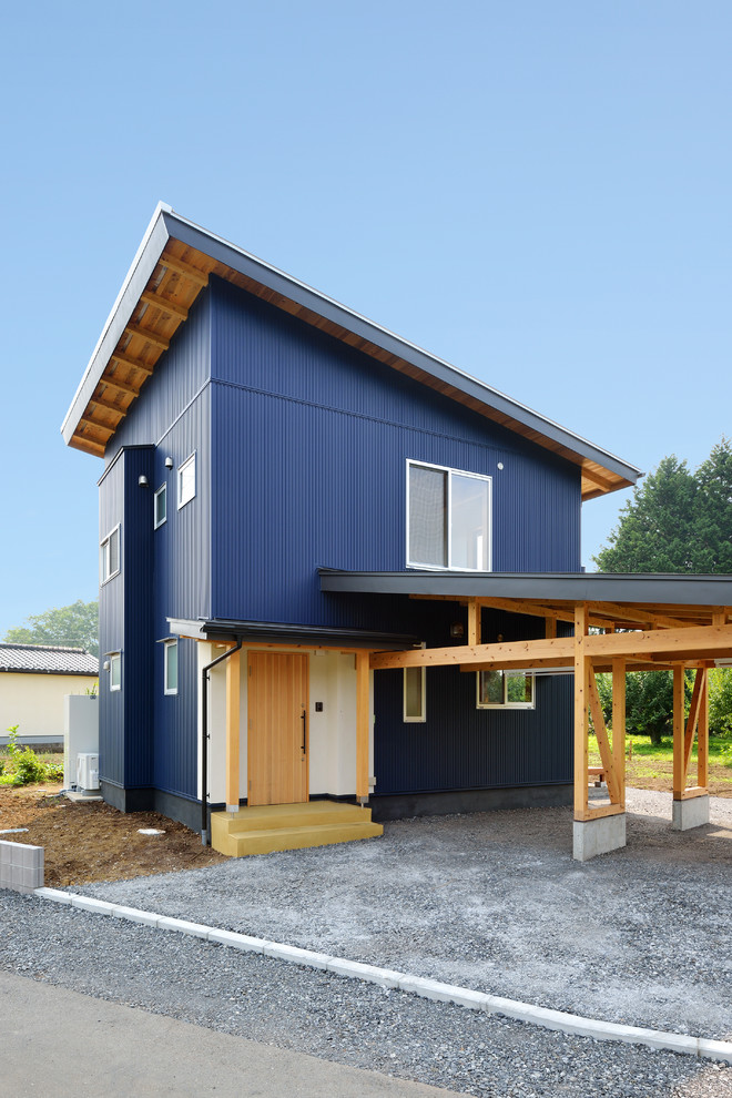 На фото: двухэтажный, синий частный загородный дом среднего размера в современном стиле с односкатной крышей