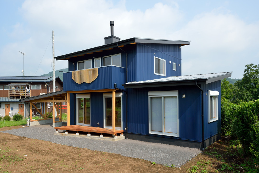 Свежая идея для дизайна: двухэтажный, синий частный загородный дом среднего размера в восточном стиле с односкатной крышей и металлической крышей - отличное фото интерьера