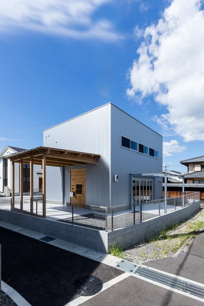 Imagen de fachada de casa gris rústica de tamaño medio de dos plantas con revestimiento de metal, tejado plano y tejado de metal