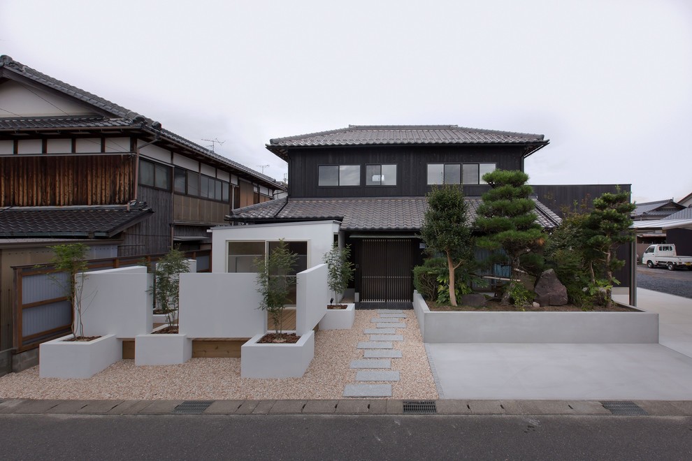 На фото: двухэтажный, деревянный, черный дом в восточном стиле с вальмовой крышей с