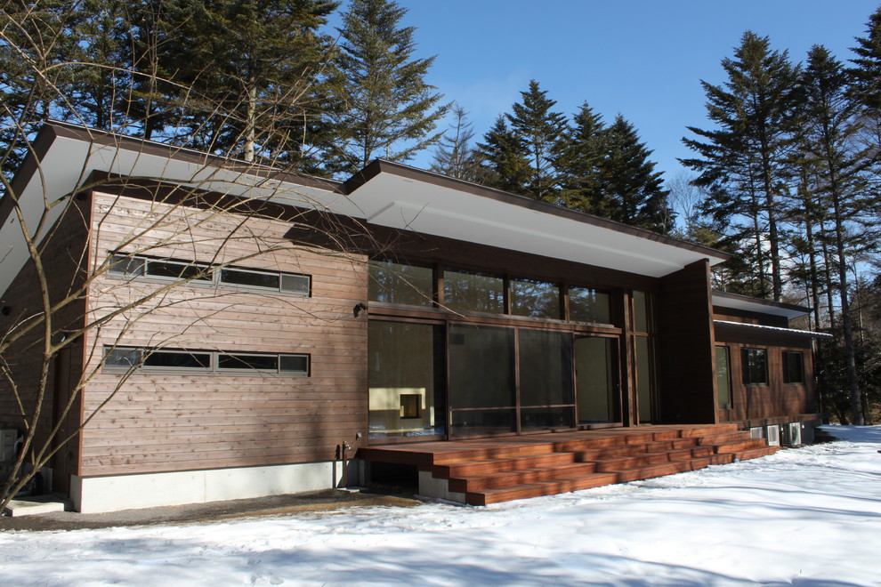 Foto della facciata di una casa marrone contemporanea a due piani con rivestimento in legno e copertura in metallo o lamiera