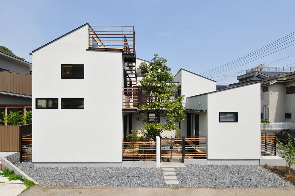 Idées déco pour une façade de maison blanche contemporaine à niveaux décalés avec un toit en appentis.