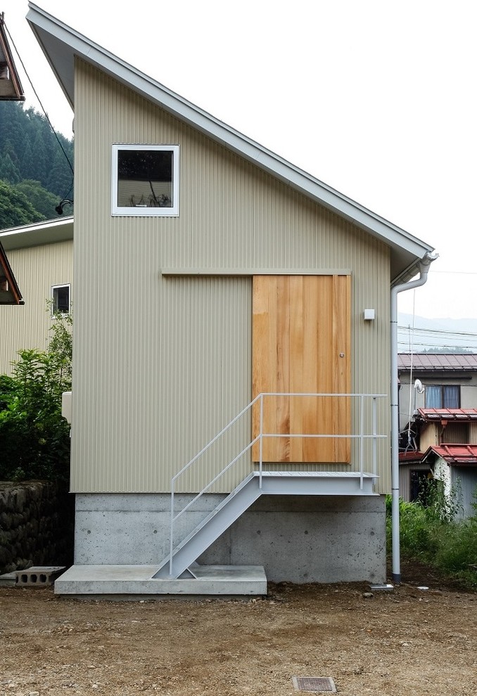 Пример оригинального дизайна: двухэтажный, бежевый дом в стиле модернизм с облицовкой из металла и односкатной крышей