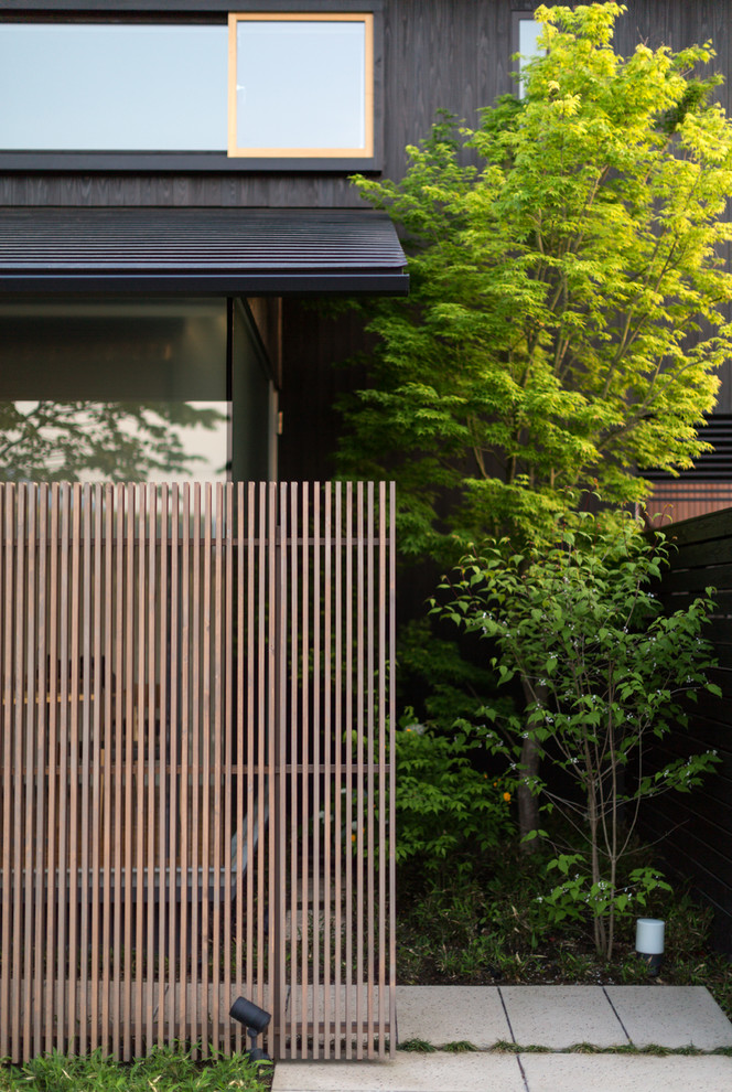 Diseño de fachada negra moderna de dos plantas con revestimiento de madera y tejado a dos aguas