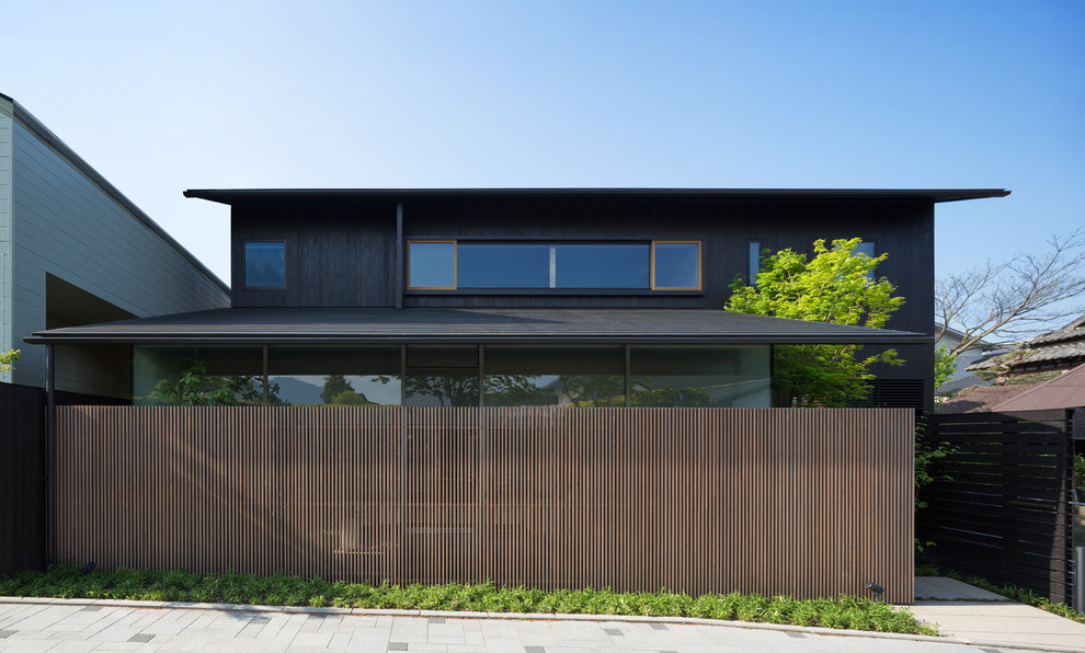 Imagen de fachada negra minimalista de dos plantas con revestimiento de madera y tejado a dos aguas