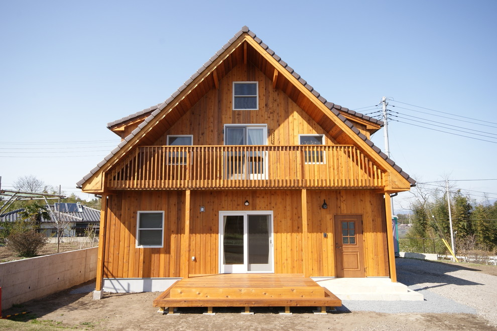 Immagine della facciata di una casa marrone etnica con rivestimento in legno