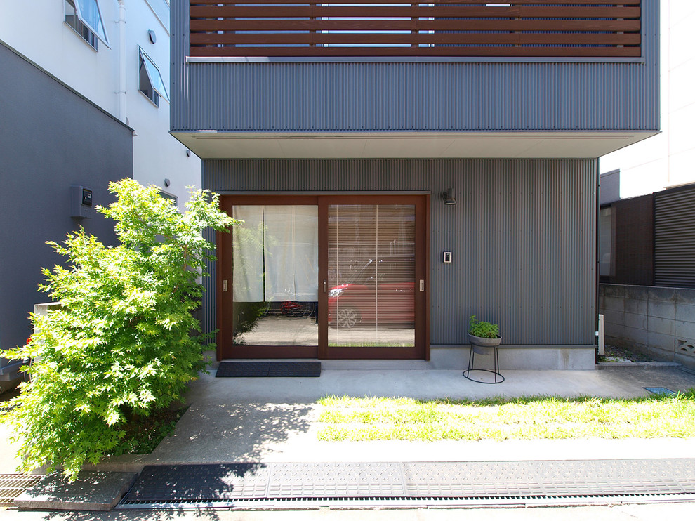 Ejemplo de fachada de casa gris urbana pequeña de dos plantas con revestimiento de metal, tejado a dos aguas y tejado de metal